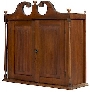 Pennsylvania or New Jersey walnut hanging cupboard, early 19th c., with a broken arch crest and re