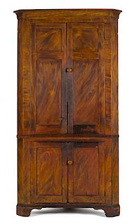 Painted pine one-piece corner cupboard, early 19th c., retaining its original orange and yellow gr