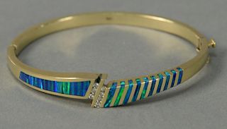 14K gold bangle style bracelet inlaid with green and blue and seven small diamonds (one small diamond missing). 24.5 grams.