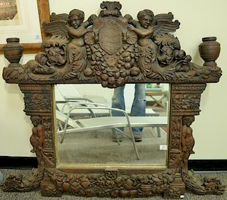 Large figural Italian classical style oak mirror having carved putti figures, grapevines, and fruit wreaths. 43" x 52"