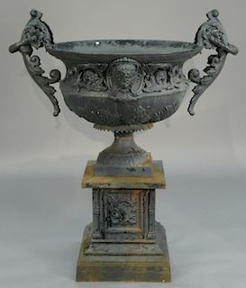 Victorian iron urn with large foliate arms and wreath rings with sheep face on either side on pedestal with square base with 