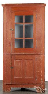 Painted pine one - piece corner cupboard, 19th c., retaining an old red surface, 83'' h., 39'' w.