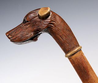 A 19TH C. CARVED DOG HEAD GLOVE HOLDING WALKING STICK