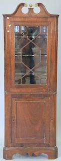 Small mahogany corner cabinet with broken arch top over glazed glass door over panel door. ht. 75in., wd. 27 in., dp. 12in.