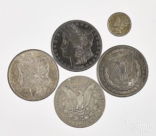 Four Morgan silver dollars, together with a Mercury dime.