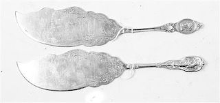 Two American Silver Fish Slices, , each with handles decorated with classical scenes, the blades chased with foliate and volu