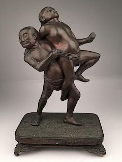 Japanese bronze figurine of two Sumo wrestlers in combat.<BR>Mounted on a four foo