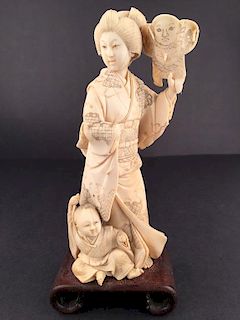A antique carved Geisha standing holding a mask in her left hand
