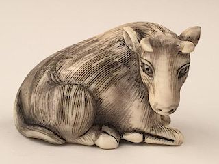 A carved Netsuke figure of an animal laying down.