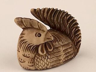 A carved Netsuke figure of a sitting hen looking back. Signed.