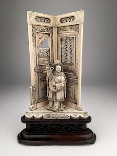 Carved  scene of a lady playing a mandolin in an architectural setting.