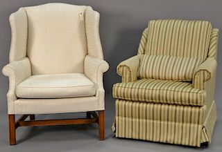 Two upholstered living room chairs including a white wing chair and a striped upholstered chair.