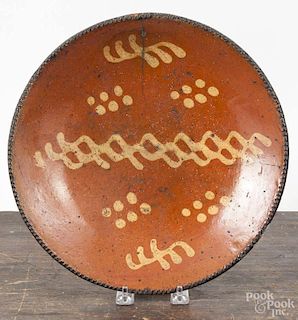 Pennsylvania redware shallow bowl, ca. 1800, with slip decorated dots and triple wavy lines, 11 1/2''