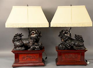 Pair of large carved hardwood foo dogs with glass eyes, on rectangle stands made into table lamps. 
total ht. 32in., wd. 16 1