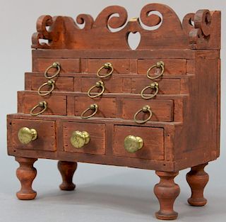 Miniature Federal chest having open work carved gallery over twelve drawers all set on turned legs in red paint (gallery repa