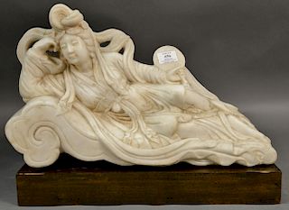 Large marble sculpture of a Guanyin with flowing robe holding a fan and lying on a lotus form base.  ht. 12in., lg. 20 1/4in.
