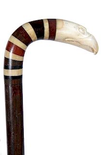 57. Nautical Eagle Cane- Ca.1800- A carved whale’s tooth eagle with wood and bone spacers, exotic wood shaft and a brass fe