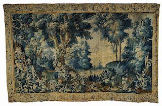 Flemish Verdure Tapestry, 18th century, depicting a landscape with deep foliage, and mountains in the distance, with a foliat