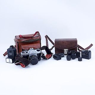 Grouping of Pentax K1000 and Pentax Auto 110 Film Cameras in Leather Traveling Cases.
