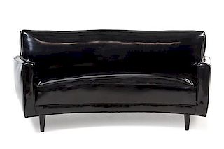 American, c.1950, a black vinyl upholstered curved sofa