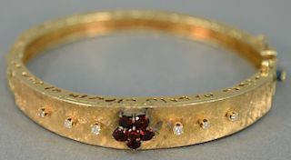 14K bangle bracelet, set with small diamonds and red stones. 21 grams.