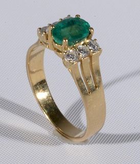 18 karat gold ring set with center oval emerald flanked by three diamonds on either side. size 9 1/4