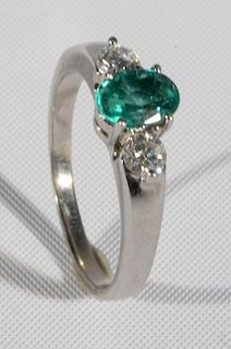 18 karat white gold ladies ring set with center emerald flanked by diamond on either side. size 7 1/2