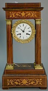 Rosewood empire mantle clock with marquetry inlays, porcelain dial with gilt surround, and brass pendulum