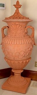Pair of Terracotta covered urns decorated with pineapple carving scrolled handles, and grape vines, set on square bases, (eac