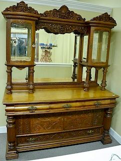 R.J. Horner oak sideboard having curio cabinet top with bowed beveled glass under carved faces, set on base of doors and draw