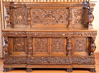 Oak sideboard having carved panel back with compote of fruit supported by winged griffins set on cabinet having three carved