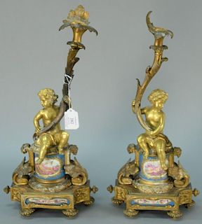 Pair of French gilt bronze candle holders mounted with putti on base with porcelain panels, one made into lamp. 
ht. 17in. Pr