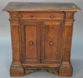 Continental walnut cabinet having rectangular top over one drawer over two doors flanked by fluted pilasters, set on step mol