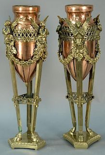 Pair of copper urns in brass holders with winged women on fluted legs ending in hoof feet on three sided base