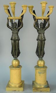 Pair of bronze and gilt bronze figural candelabra, each with three lights in ring above winged angelic figure, set on ball on