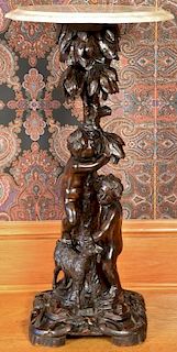 Carved walnut black forest pedestal having two children and a goat below a shaped marble top. ht. 32in., dia. 16in. Provenanc