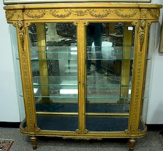Louis XVI style gilt vitrine having onyx top on cabinet with bowed glass sides, glass shelves, and mirror back, all set on tu