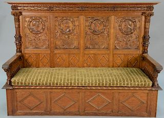 Carved oak bench back with carved knights and maidens and ram's head hand rests with spindled arms with lift seat