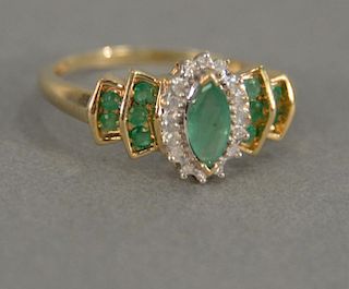 Ladies 14 karat yellow gold emerald cluster ring containing one center 8x4mm marquise shape emerald with a halo of sixteen me