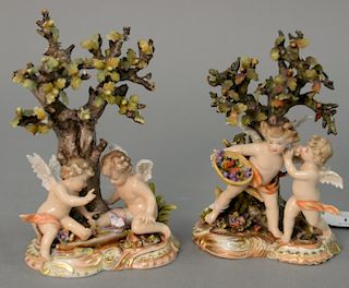 German porcelain pair of 19th century cherub figural groups having two cherubs, each under a tree, marked on bottom with cros