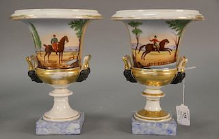 Pair of French porcelain urns with equestrian scene and two handles mounted with figural bust. ht. 9 3/4in., dia. 7 1/2in.