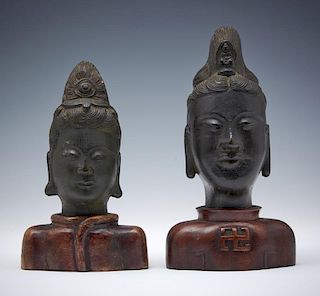 Grouping of two bronze Buddha heads on wood stands
