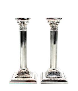 * A Pair of Silvered Metal Candlesticks, , each in the form of a Corinthian column and raised on a stepped square base with a