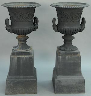 Pair of Victorian iron urns with handles and faces on stands.   height 52 inches, top diameter 22 inches  Provenance: Propert