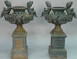 Pair of two part iron urns with putti and ram's heads, on stands, late 20th century. 
height 49 inches