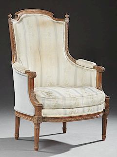 Louis XVI Style Carved Walnut Upholstered Bergere, 20th c., the arched crown flanked by finials above an upholstered arched h