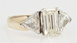 Lady's 14K Yellow Gold Dinner Ring, with a central emerald cut 1.57 carat diamond, flanked by two .75 carat trillion cut diam