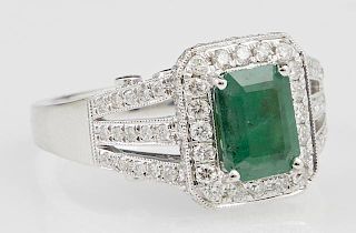 Lady's 18K White Gold Dinner Ring, with a 1.41 carats emerald within a conforming border of round diamonds, the triple split 