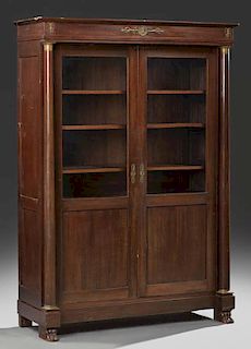 French Empire Style Carved Mahogany Ormolu Mounted Bookcase, 19th c., the rectangular crown over setback double doors with gl