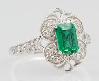 Lady's 18K White Gold Dinner Ring, with a .94 carat emerald atop a pierced lobed border of round diamonds, the sides of the b
